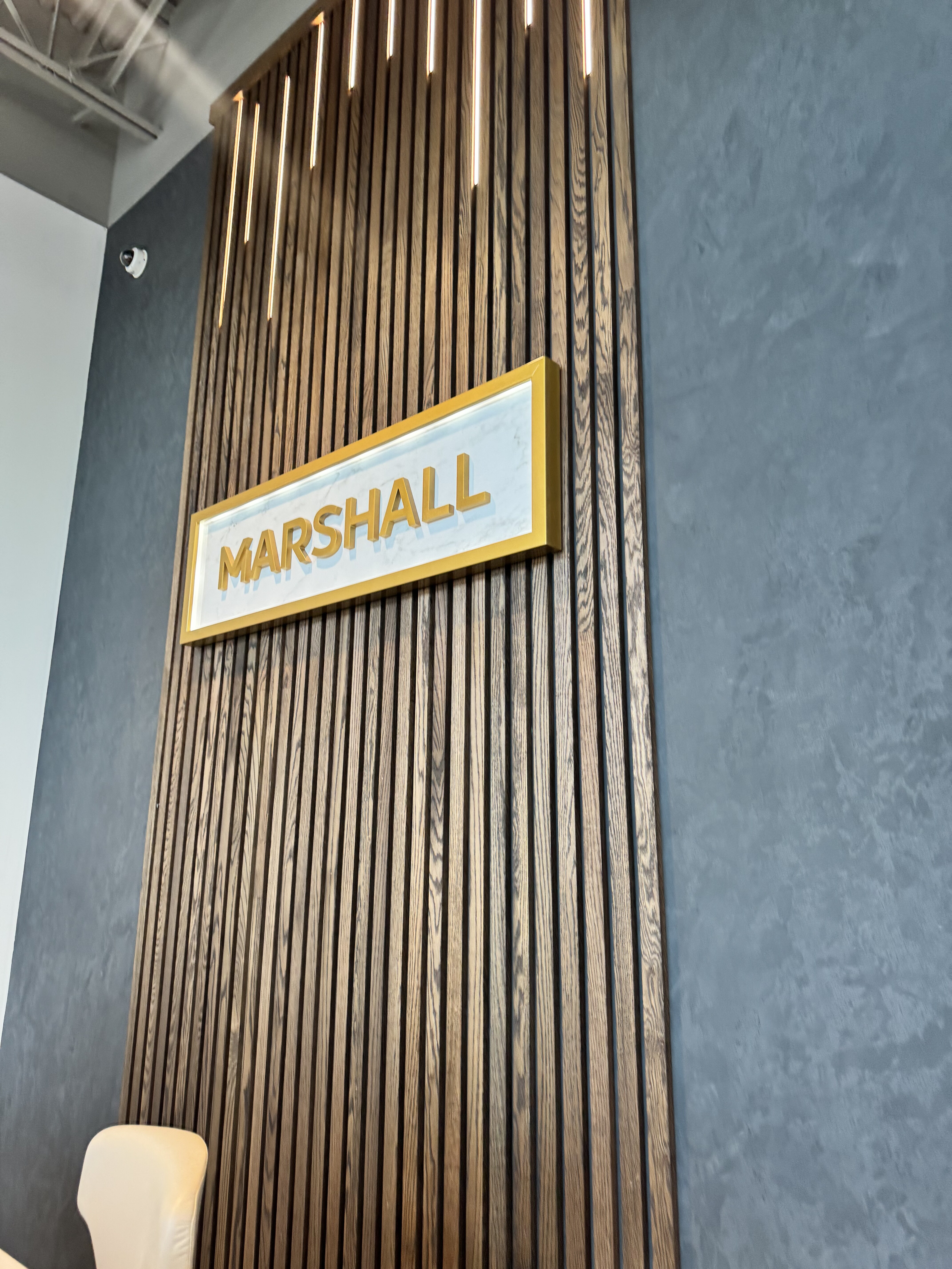 Branded wood-slat feature wall with integrated lighting and Marshall signage